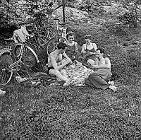 Rastande personer i park med pipa och spelkort. Två män och två kvinnor har cyklat till Långholmsparken och spelar kort på en picknickfilt i gräset.