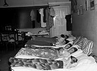 Skolbarn från landsbygden besöker Stockholm. Sex flickor ligger nedbäddade i sängar i ett klassrum.