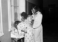 Skolbarn från landsbygden besöker Stockholm. Fyra flickor borstar tänderna iklädda pyjamas.