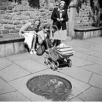 Ungt par som fotograferar sitt barn, sittandes i barnvagn.