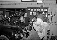 Bergengren AB, bilteknisk provningsanstalt. Män står vid en öppen motorhhuv och mekar.