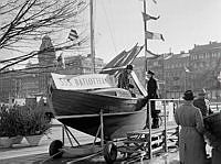Nybroplan. Stockholms Segelsällskap, SSS, säljer lotter från en segelbåt.