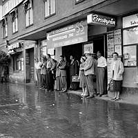 Tegelbacken. Stockholmare söker skydd för regn utanför vänthall.
