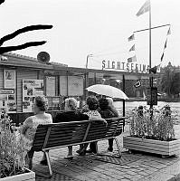 Strömgatan. Fem kvinnor sitter på en parkbänk vid ett sightseeingkontor.