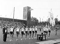 Finaldagen av SM i friidrott på Stadion. Idrottsmän står uppställda vid standar.