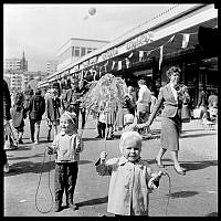 Hässelby Gårds centrum invigs. Barn med pappersvippor i folkvimlet.