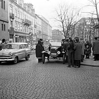 Hamngatan österut, korsningen vid Västra Trädgårdsgatan och Sagerska huset. Folksamling kring en gammal bil som stannat på gatan.