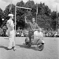 Vespa-tävling i Kungsträdgården. I tävlingen gällde det att bl a flytta ett glasvatten. En fransman rev allt som gick att riva och folket jublade då han lyckades få allt vattnet i glaset i ansiktet.