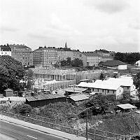 Östgötagatan 80. Folksamhuset byggs. Vy från Skansbron mot Bohusgatan, Stadens trädgård och Högre allmänna läroverket för flickor å Södermalm (Södra flickläroverket).