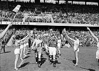 Råsundastadion. Fotbollsmatch mellan Sverige-Danmark. Spelarna på väg in på planen mellan en rad av hejarklackstjejer.