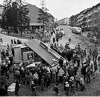 En buss har kört in i en kiosk. Korsningen Sparbanksvägen/Mellanbergsvägen. 
På ändhållplatsen började den tomma bussen med låsta bromsar rulla nedför backen, rakt mot en kiosk med en kö av barn.
