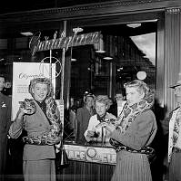 Cirkusdamerna Rose och Lydia ben Ahmed med pytonormar runt halsen. Damerna gör här framför NK:s glasskiosk vid Hamngatan 18-20 reklam för Cirkus Mijares-Schreiber föreställning.