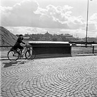 Strandvägen. Kvinna cyklar i blåsväder.