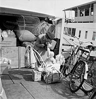 Södra Blasieholmshamnen, nuvarande Strömkajen. Sommarflyttande stockholmare lämnar staden och åker ut till skärgården. En mamma gör sig och sitt barn redo för att gå på skärgårdsbåten.