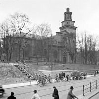 Maria Magdalena kyrka. Vy mot kyrkan och Hornsgatan från Hornsgatspuckeln. Cyklister och hästtransport på gatan.