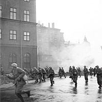 Stridsövningar på Riddarholmen. I skydd av utlagda rökridåer rusar stormbåtstrupper fram på Södra Riddarholmshamnen, mot Birger Jarls torg.