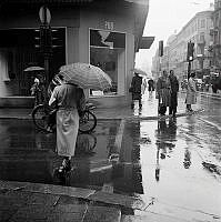 Drottninggatan 63, hörnet av västra PUB-huset. Korsningen Drottninggatan/ Kungsgatan västerut. Regnväder.