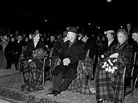 Kungsträdgården. Stockholms 700-års jubileum invigs med framträdanden. Kungaparet och prinsessan Sibylla sitter inlindade i filtar och tittar.