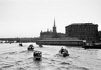 Riddarfjärden. Småbåtars hemkomst från söndagstur. T.v. Centralbron och tunnelbanebron under uppbyggnad. Riddarholmskyrkan i fonden. T.h. flytande fiskhall vid Kornhamnstorg och Cederlundska huset.