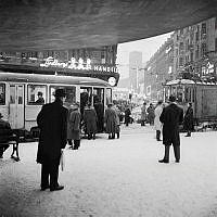 Stureplan under Svampen, vy mot Kungsgatan. Folk kliver på spårvagn på Birger Jarlsgatan i snöyran.