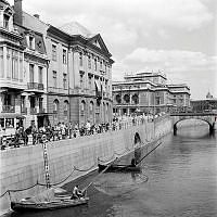 Norrström och Strömgatan 16-18, vy från Riksbron. Fiskebåtar, håvbåtar, och åskådare. Operahuset i fonden.