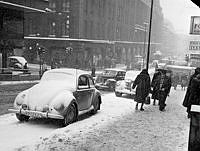 Hörnet Hamngatan-Regeringsgatan. Gatumiljö i snöväder. T. v. Hamngatan 18-20, NK (Nordiska Kompaniet).