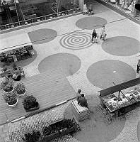 Torg (Lilla Hötorget) bakom entrén till Hötorgshallen, vid Slöjdgatan 14 med gångpassage till Sergelgatan.Torget överbyggt 1995.