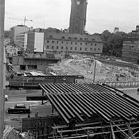 Vy över rivna kvarteret Kajan. Klarabergsviadukten byggs. T.v. Klarabergsgatan och i fonden Klara kyrka och Klara västra kyrkogata. T.h. Klara Vattugränd och i förgrunden Vasagatan.