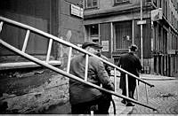 Hörnet  Herkulesgatan och Norra Smedjegatan. Karl Gunnar Larsson på cykel med stege. I fonden Linds kaffestuga.