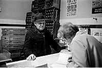 Norra Smedjegatan 5. Man som handlar i Maja Erikssons mjölkbutik. Maja Eriksson skriver in summan i sin kassabok.