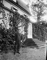 F.U Wrangel klädd i kostym och halmhatt står framför en villa .