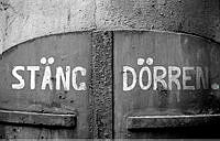 Norra Smedjegatan. Dörrpar på gård med påmålade texten Stäng Dörren.